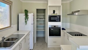 Une cuisine compacte équipée d’un four à micro-ondes intégré, d’un four classique et d’un évier en acier inoxydable.