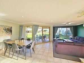 Uma área de refeições com uma mesa, cadeiras, um sofá e vista para o exterior.