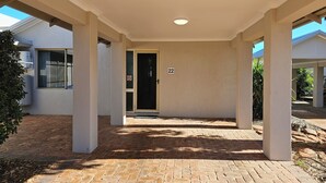A covered outdoor area with a brick floor, columns, and a door marked with the number 22. - Pelican Shore Villa 22 - Kalbarri WA (Kalbarri)