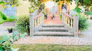 A stone staircase leading to a gated entrance, surrounded by potted plants and a well-maintained garden. - La Almadraba, Chiclana de la Frontera (Chiclana de la Frontera)