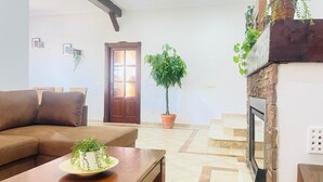 A living room with a brown sofa, a wooden coffee table with a plant, a fireplace, and a door leading to another room. - La Almadraba, Chiclana de la Frontera (Chiclana de la Frontera)