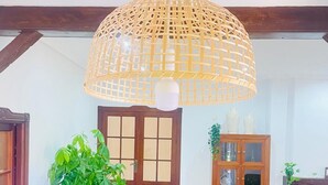 A spacious living room with a wooden dining table, wicker chairs, a large woven pendant light, a potted plant, and a wooden cabinet with glass doors. - La Almadraba, Chiclana de la Frontera (Chiclana de la Frontera)