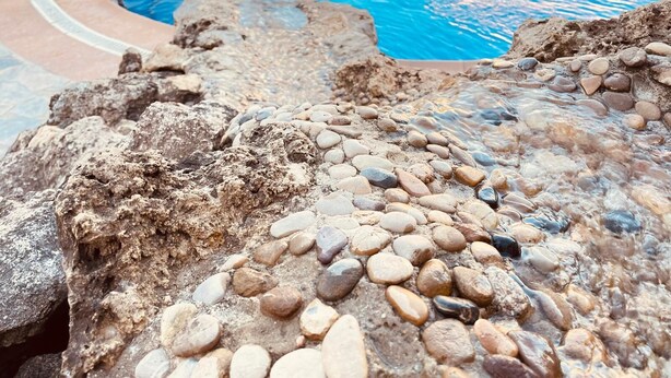 A swimming pool with a rocky edge and a metal ladder. - La Almadraba, Chiclana de la Frontera (Chiclana de la Frontera)
