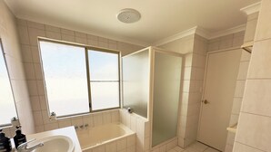 A bathroom with a bathtub, a shower, a sink, and a window. - Pelican Shore Villa 14 - Kalbarri WA (Kalbarri)