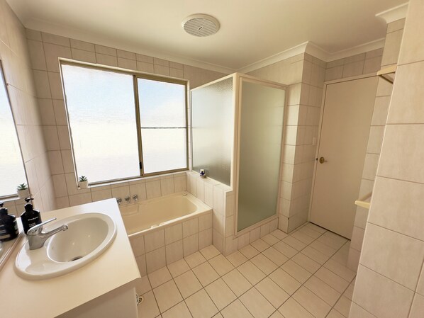 Un baño con bañera, ducha, lavabo y ventana.