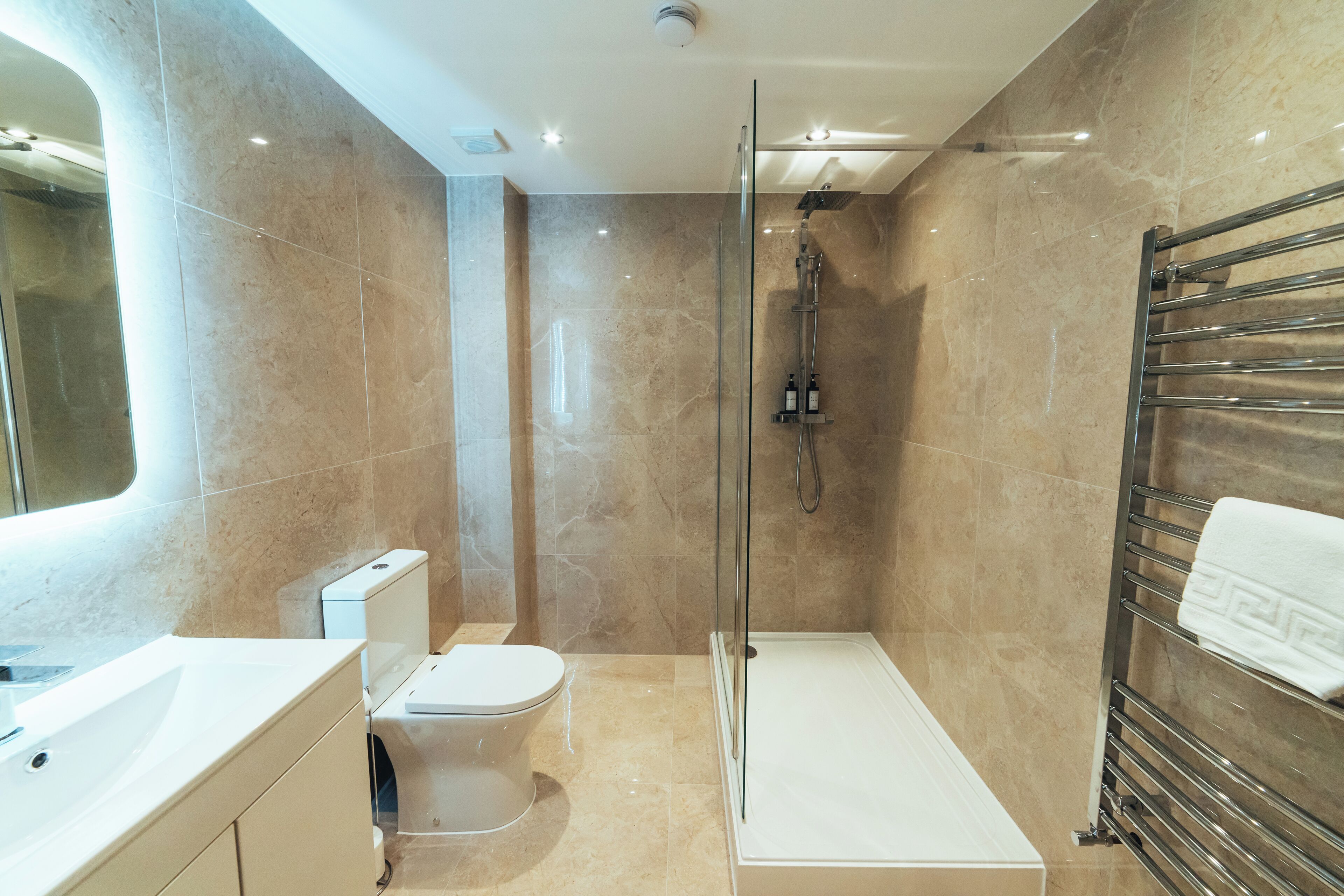 Un baño moderno con ducha acristalada, inodoro blanco y lavamanos empotrado.