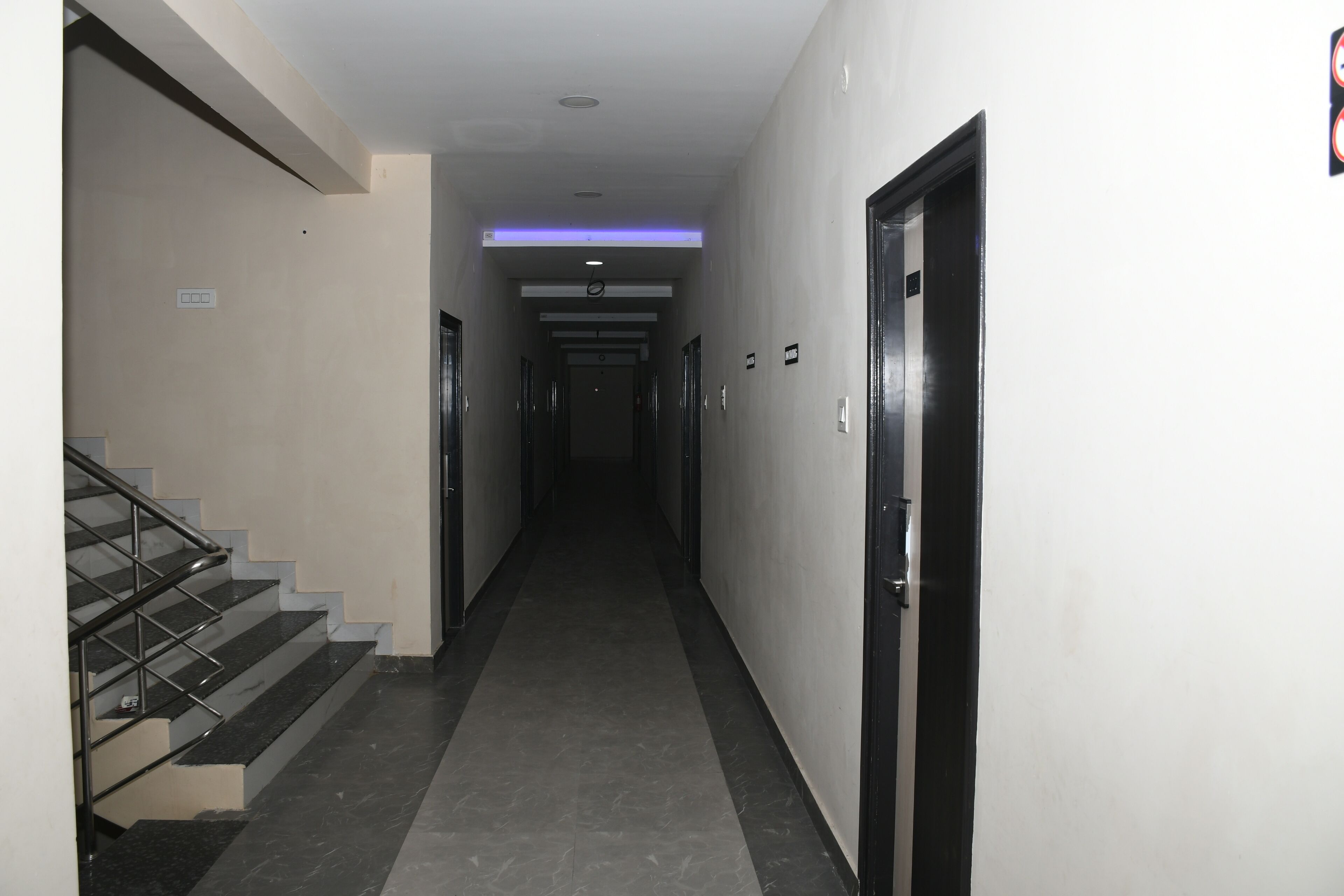 A hallway with a staircase on the left, doors on the right, and a ceiling light.