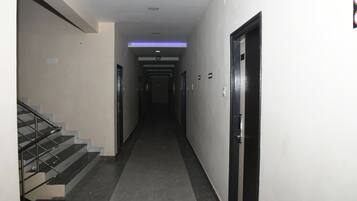 A hallway with a staircase on the left, doors on the right, and a ceiling light.
