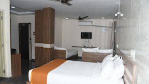 Een hotelkamer met een groot bed, een bureau, een televisie en een plafondventilator.