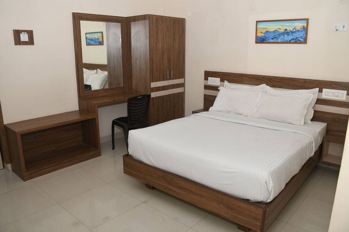 A bedroom with a wooden bed, a wardrobe, a desk, and a chair.