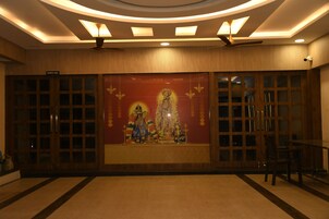 A dining hall with a large mural, wooden doors, and a ceiling fan.