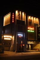 A building with illuminated signs for "ROOMS" and "COZY NEST" indicating hotel or lodging services.