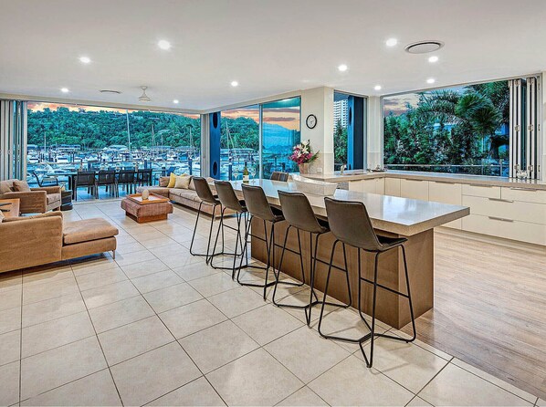 A modern kitchen with a bar area, large windows, and a view of a marina.