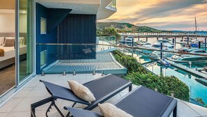 A balcony with two sun loungers and a view of a marina with boats.