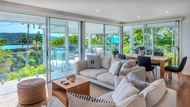 A modern living room with a large glass door leading to a balcony overlooking a scenic view. - Oasis 21, Oasis 21 on Hamilton island (Hamilton Island)