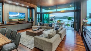 A modern living room with a large TV, comfortable seating, and a view of the ocean. - Yacht Club Villa 29, Yacht Club Villa 29 on Hamilton Island (Hamilton Island)