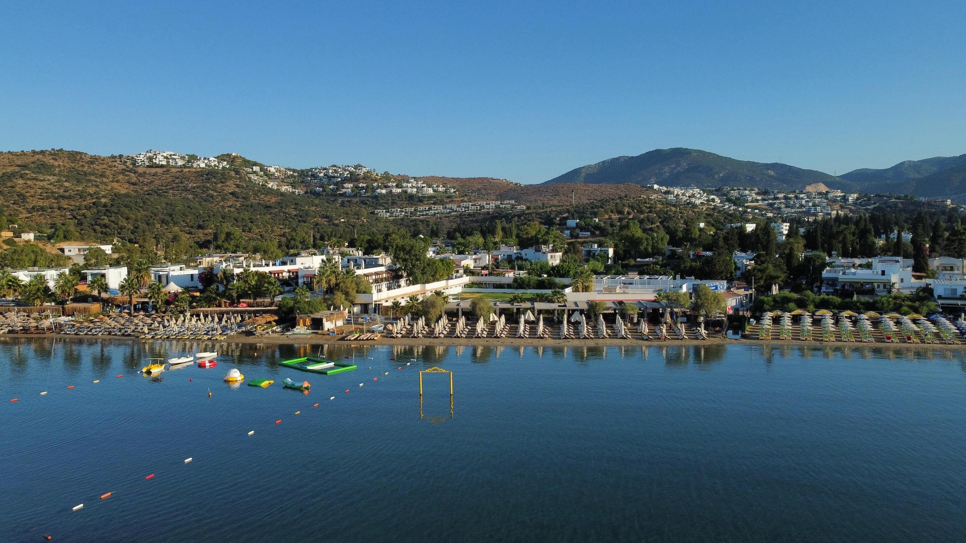 A coastal town with a marina, boats, and beach umbrellas.