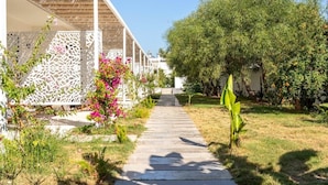 A pathway leading to a building with a white facade and a covered area with a woven roof. - SEA SOUL OTEL (Bodrum)