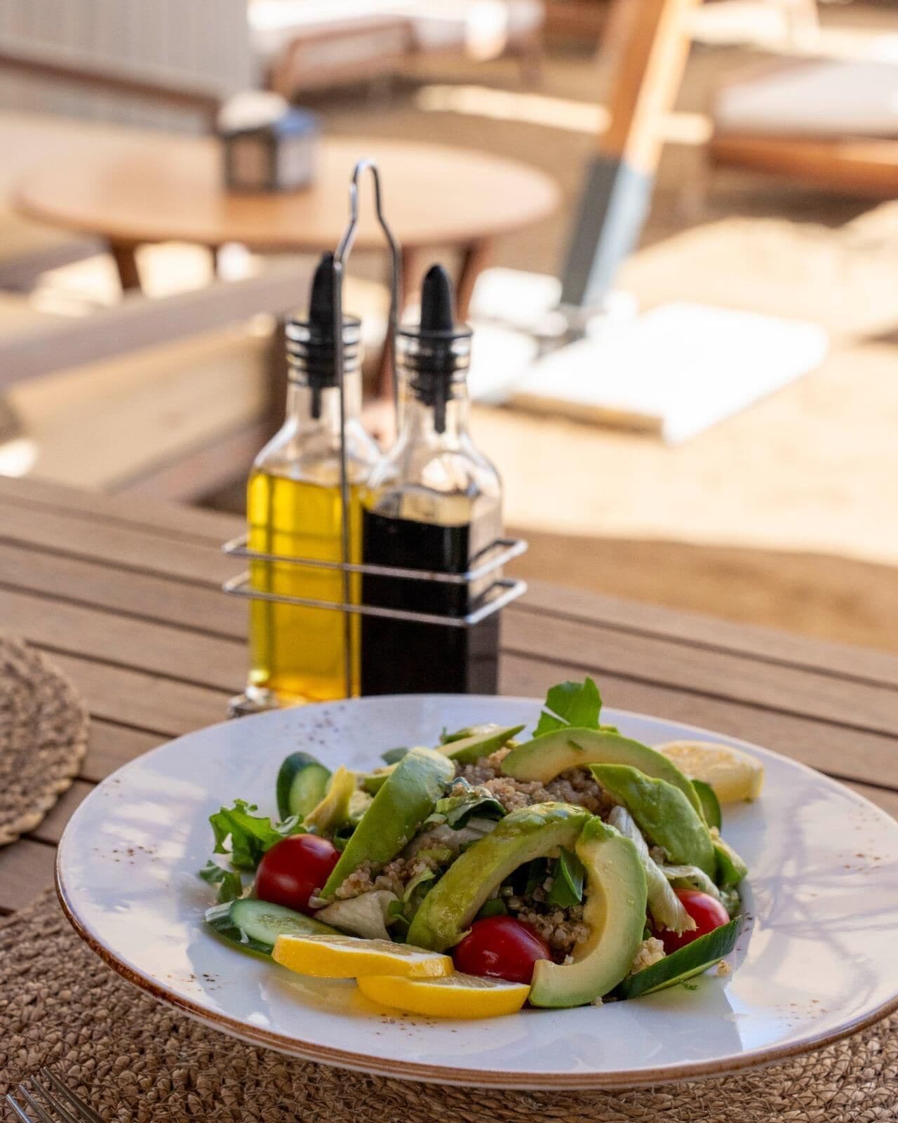 A plate of salad with vegetables and a lemon wedge on a table.