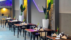 Una sala ristorante con diversi tavoli, ognuno apparecchiato con tovaglioli bianchi, piatti e posate.