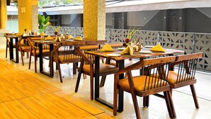 Un ristorante con tavoli e sedie in legno, un pavimento piastrellato e vista sul verde.