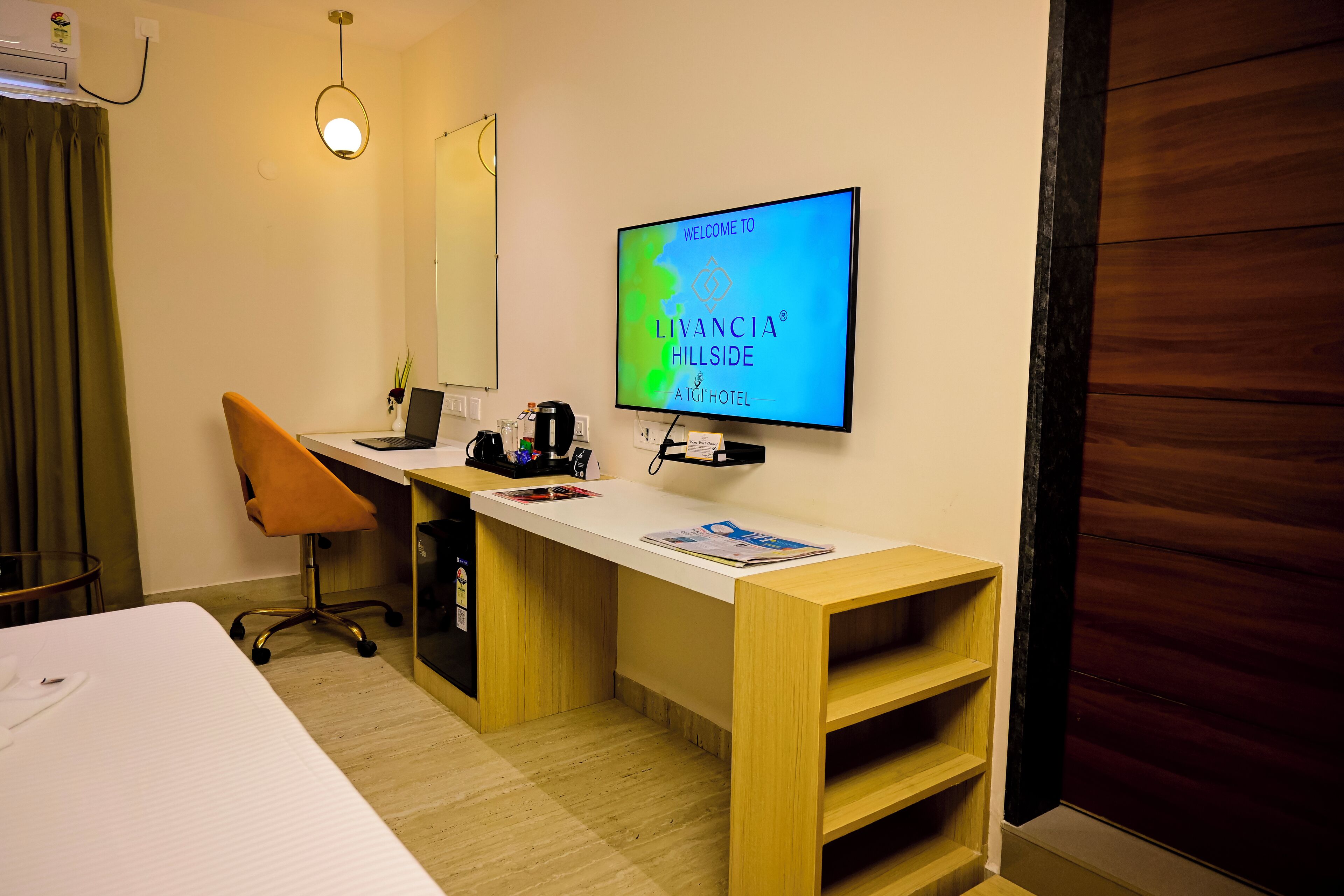 Hotellihuone, jossa on sänky, työpöytä, tuoli, televisio ja puinen vaatekaappi.