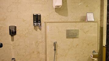 Un baño moderno con pared de mármol, ducha con cerramiento de vidrio, inodoro y toallero.