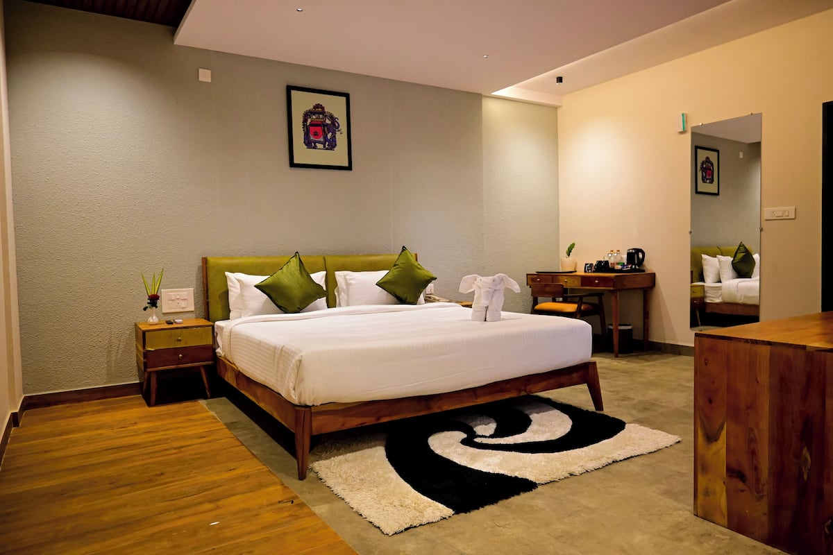 Una habitación de hotel ordenada con cama, mesita de noche y un pequeño escritorio con silla.