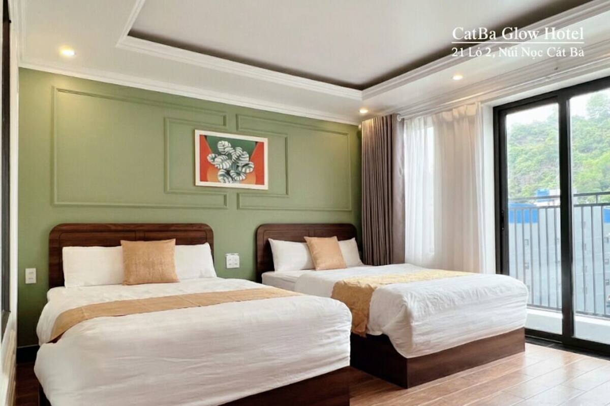 A hotel room with two beds, a green accent wall, and a large window with a view.
