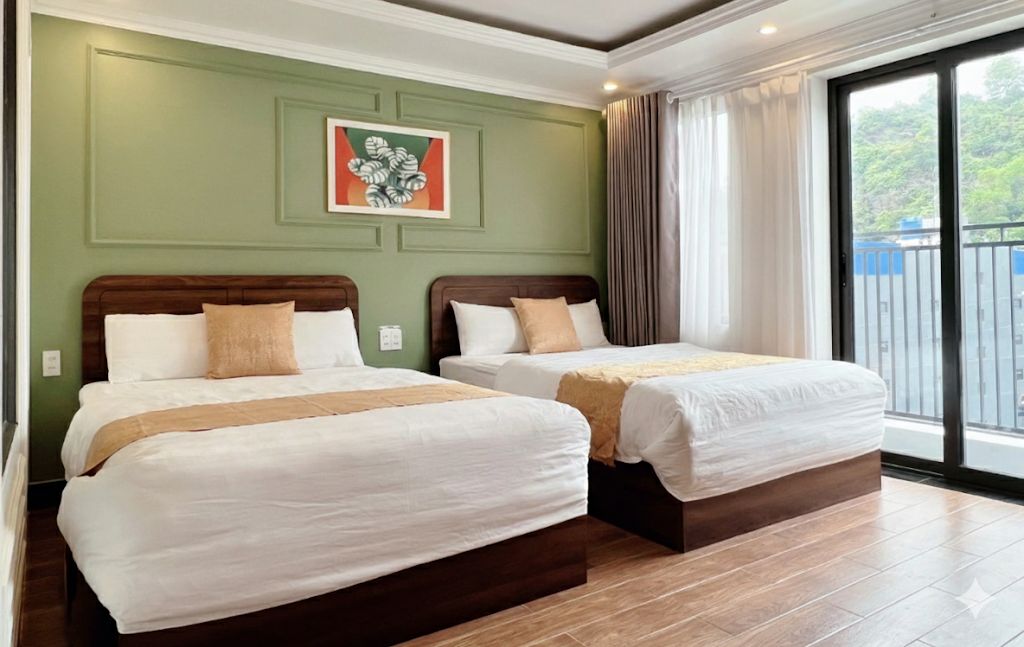 A hotel room with two beds, a green accent wall, and a large window with a view.