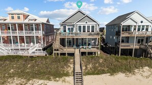 A beachfront property with multiple levels, wooden decks, and a sandy beach in the foreground. - In Spiaggia (at the beach) #185 - 6 BD Oceanfront in the heart of Surf City! (Surf City)