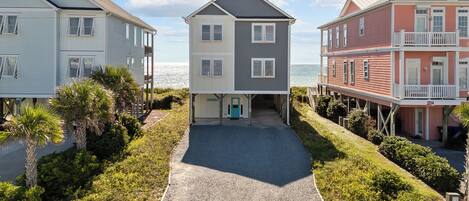A coastal property with a central building, two side buildings, and a gravel driveway.