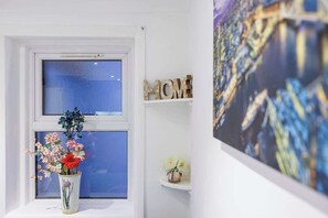 Enjoy the serene view from the large window, featuring a vase with flowers and a personal touch with the word 'HOME' displayed on the shelf.