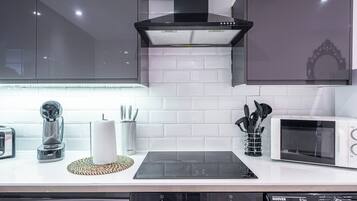 A modern kitchen with a built-in microwave, toaster, and a digital clock displaying 1345.
