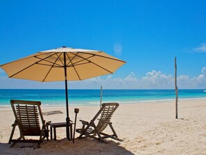 Relax in comfort under a shaded area with two lounge chairs, a table, and a stool.