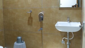 A bathroom with a shower, a sink, and a toilet. - Anika Suites (Hyderabad)