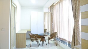 A room with a round table and four wicker chairs, a wardrobe, and a window with curtains. - Anika Suites (Hyderabad)