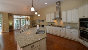 A spacious kitchen with granite countertops, white cabinetry, and stainless steel appliances. - BEAUTIFUL HOME IN THE HIGHLY SOUGHT AFTER CANAL CORKRAN (Rehoboth Beach)