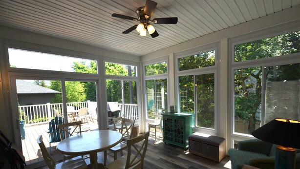 A sunroom with large windows, a ceiling fan, and a dining area with chairs and a table. - BEAUTIFUL HOME IN THE HIGHLY SOUGHT AFTER CANAL CORKRAN (Rehoboth Beach)