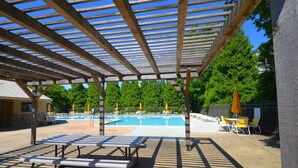 A covered outdoor area with a pool, lounge chairs, and umbrellas. - BEAUTIFUL HOME IN THE HIGHLY SOUGHT AFTER CANAL CORKRAN (Rehoboth Beach)
