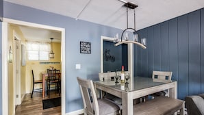 A dining area with a glass table, four chairs, and a chandelier.