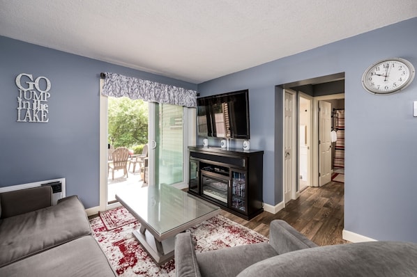 A living room with a glass coffee table, grey sofas, a fireplace, and a TV.