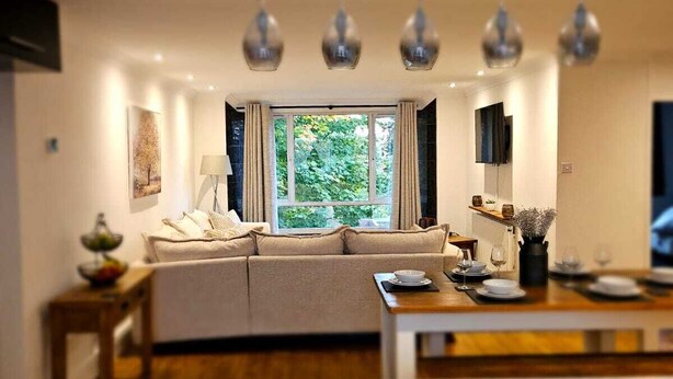 Una sala de estar moderna con sofá, mesa de comedor y área de cocina.