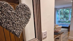 Una habitación con piso de madera, pared blanca y un espejo grande decorado con forma de corazón.