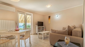 Una sala de estar moderna con comedor, sofá, televisor y balcón con toldo amarillo.