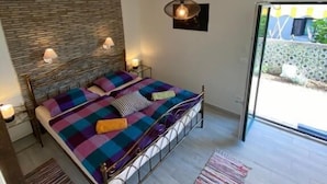 Un dormitorio con cama, lámpara colgante, ventana y vistas al exterior.