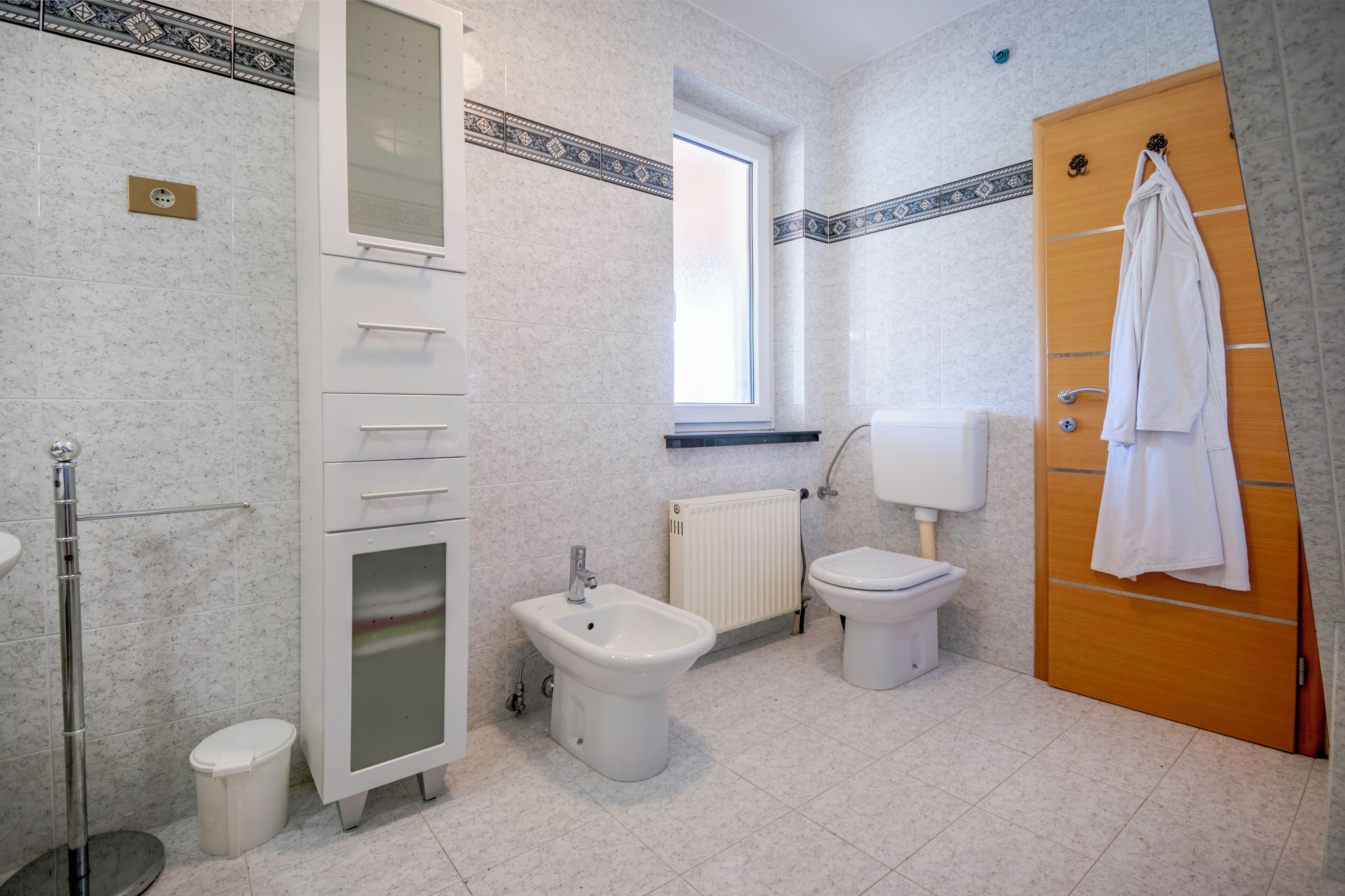 Une salle de bain équipée d’un bidet, de toilettes et d’un porte-serviettes.