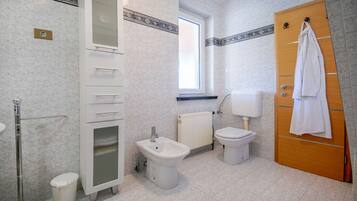 Une salle de bain équipée d’un bidet, de toilettes et d’un porte-serviettes.