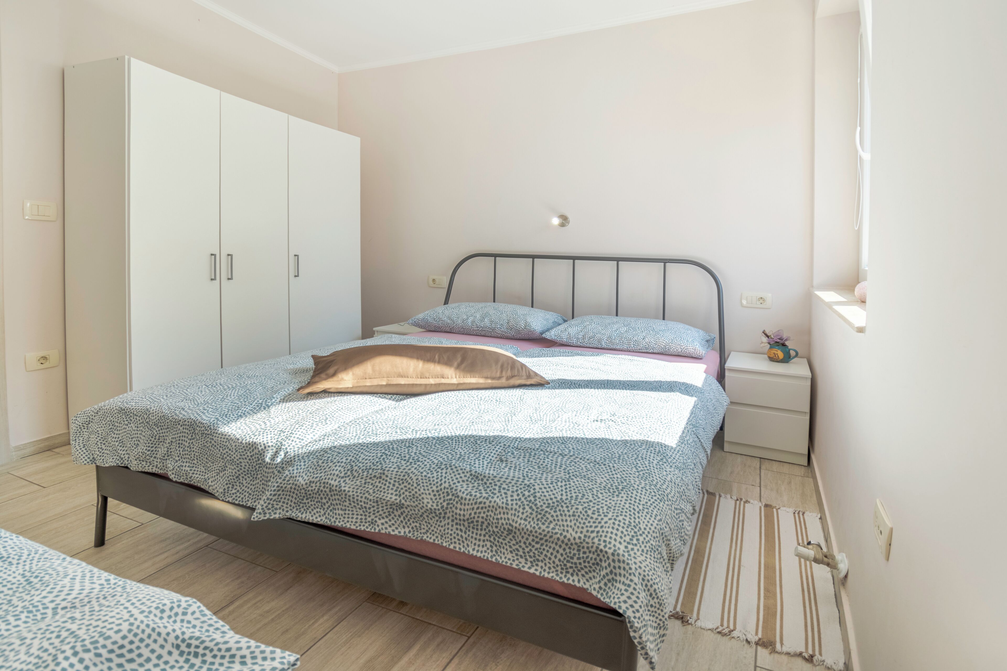 Ein Schlafzimmer mit einem Bett, einem Kleiderschrank, einem Nachttisch und einem Fenster.