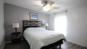 A bedroom with a bed, two bedside lamps, a ceiling fan, a framed picture on the wall, and a window with curtains. - 334 N Harbor - Perfect Place to getaway & relax! (Port Mansfield)